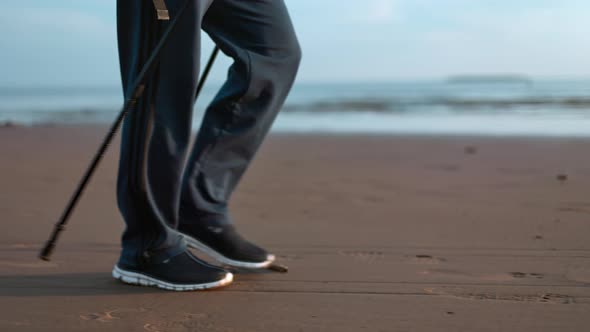 Elderly Man Legs Scandinavian Walking Stick Healthy Lifestyle Sport Hobby at Sea Sand Beach Closeup alt