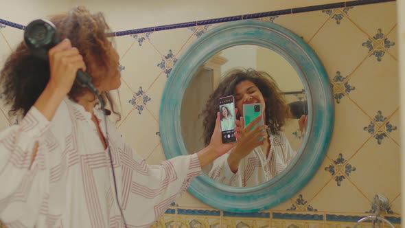 Cheerful Millennial African American Woman Drying Her Hair and Recording Selfie Video on Cell at