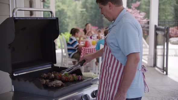 Man cooking with grill at backyard barbeque