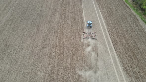 Birds eye view of farmer working field in preparation for planting with evenly spaced rows.