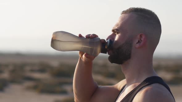 Sideangle Shot of Athletic Man Drinking Water During Exercise Break
