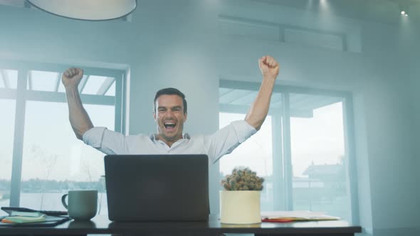 Happy Business Man Getting Good News on Laptop Computer at Remote Workplace alt