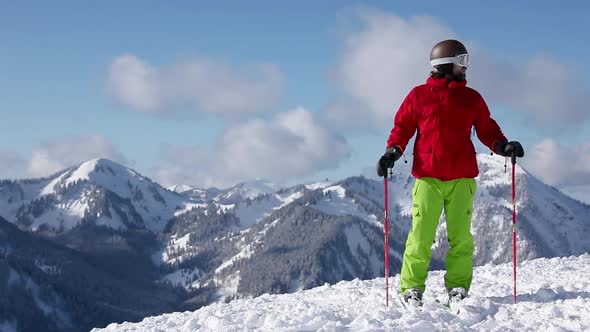 Skier taking in scenery and pointing to mountains with ski pole alt