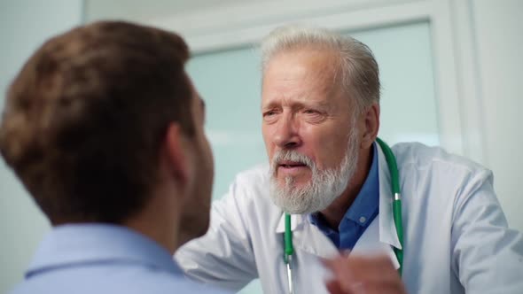 Closeup of Mature Physician Otolaryngologist Examining Maxillary Sinuses of Male Patient Coming for alt