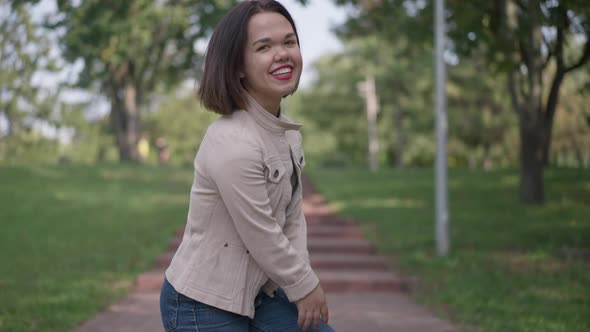 Back View Joyful Caucasian Woman with Dwarfism Laughing Walking Upstairs in Park alt