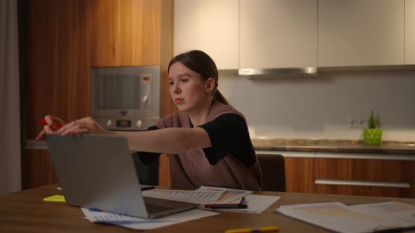 Portrait of a Woman Working Remotely in a Home Office at a Desk with a Laptop and Notes Data on a alt