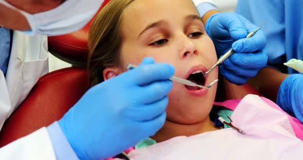 Dentist and nurse examining a young patient with tools alt