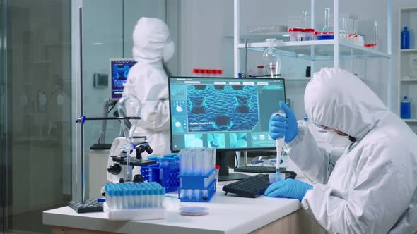 Scientist Wearing Coverall Examining Drug Discovery with Micropipette alt