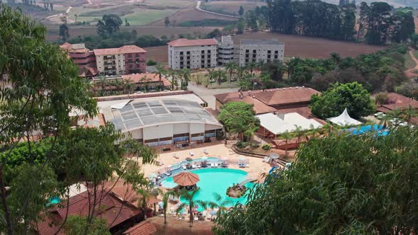 Unrecognizable people enjoying swimming pool on sunny day. Aerial descending and revealing shot thro alt