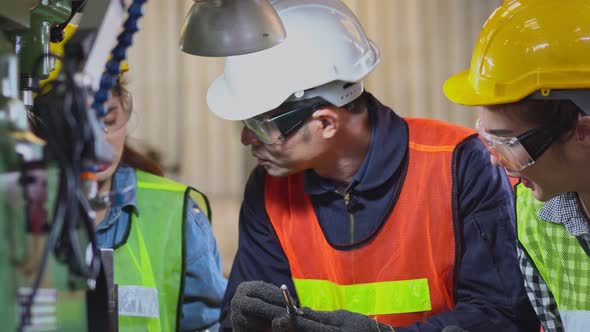 Asian male foreman showing case study of factory machine to trainees alt