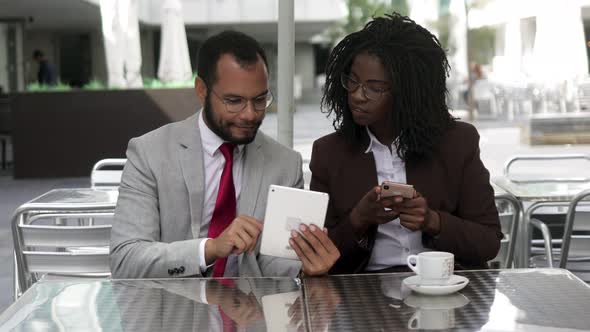 Cheerful Colleagues Using Digital Devices at Cafe alt