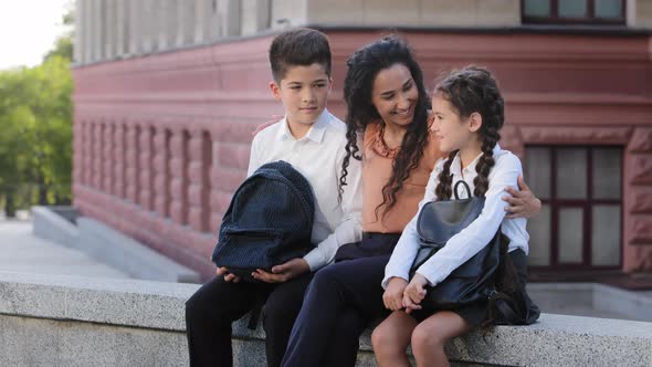 Hispanic Family Woman Mother Mommy Teacher Sitting Outdoors on Background of School Building with alt