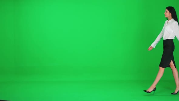 Young Businesswoman in a Suit Walks on a Green Background Chroma Key Template alt