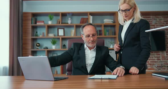 Female Assistant Bringing Financial Reports to Her Serious Purposeful Company Manager for Signature alt