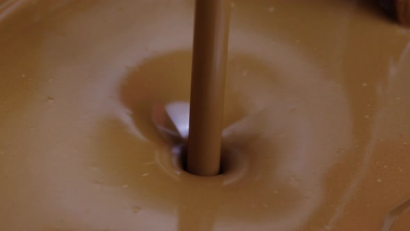 Jet of Molten Dark Chocolate Pours Into Container Forming Suction Funnel