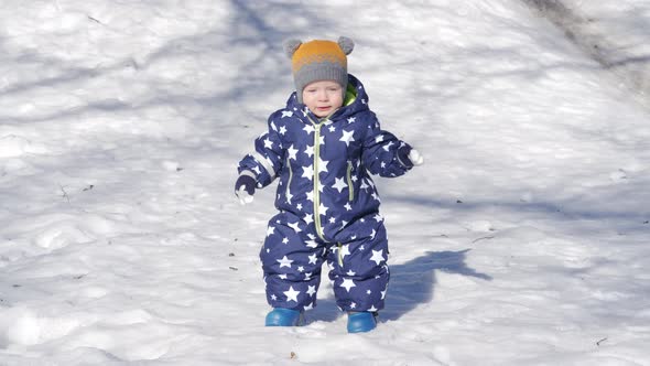 Kid Takes First Steps in the Snow in Winter 1 Year Old Baby Boy Learning to Walk in the Park alt