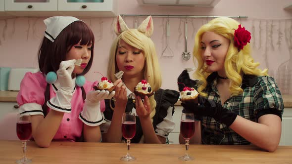 Joyful Lovely Multicultural Women Cosplayers Eating Tasty Cupcakes at Home alt