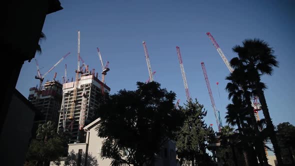 Lots of tower cranes, construction of residential buildings. Low angle view of construction site alt