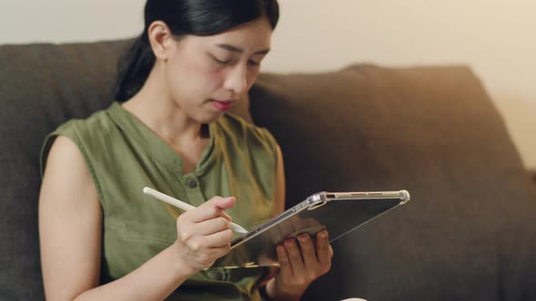 Asian female reading news on her digital tablet.