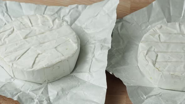 Two Camembert cheese head on white paper on cutting board. Preparation for grilling