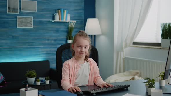 Portrait of Child Sitting at Desk with Computer for Online Lessons alt
