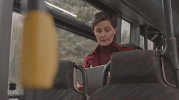 Businesswoman Reading Document on Bus alt