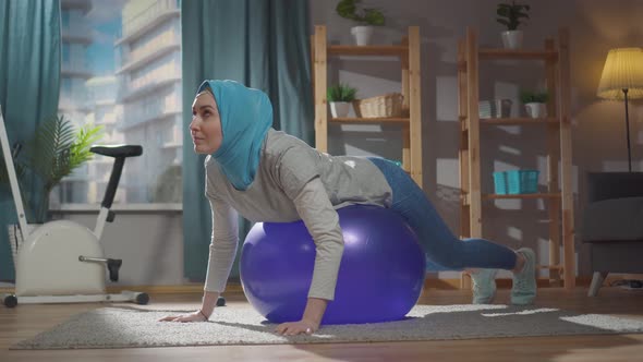 Sporty Muslim Woman is Engaged in Sports Exercises on a Gymnastic Ball at Home alt