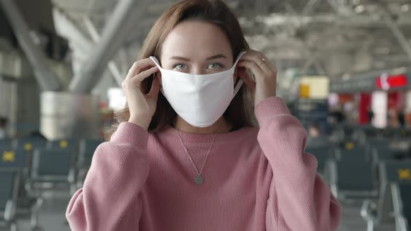 Portrait of a Woman Put on Medical Mask Looking Straight at Camera in Airport Terminal Preventing alt