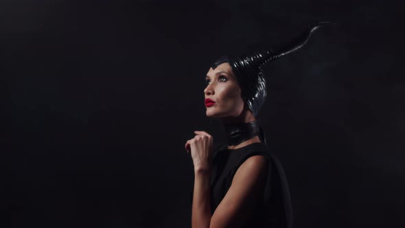 Beautiful woman from a fairytale dressed in black with horns on her head and red lipstick, looking u alt