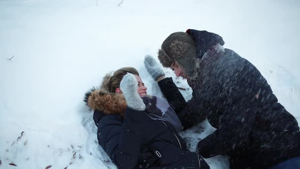 A Girl and Guy Lie in the Snow Fool Around Throw Snow Have Fun Childhood alt