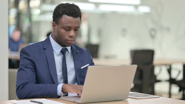 African Businessman Looking at Camera While Working on Laptop alt