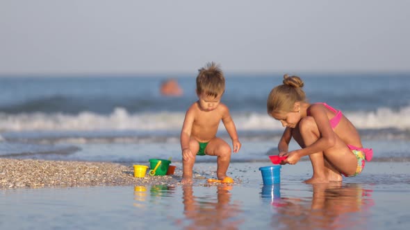 Older Sister Playing with Younger Brother Aground Near the Shore on Summer Vacation alt