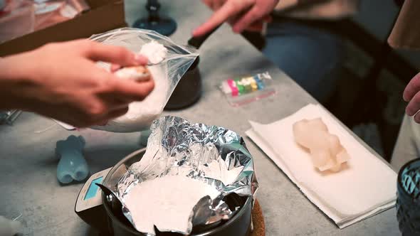 Few women occupied with hand made candles production, adding wax to a pot. Slow motion alt
