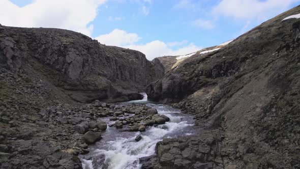 Beautiful Rocky Waterfalls With Blue Sky and White Clouds in Background alt