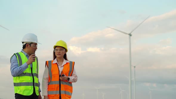 young engineer team talking and working against wind turbine farm alt