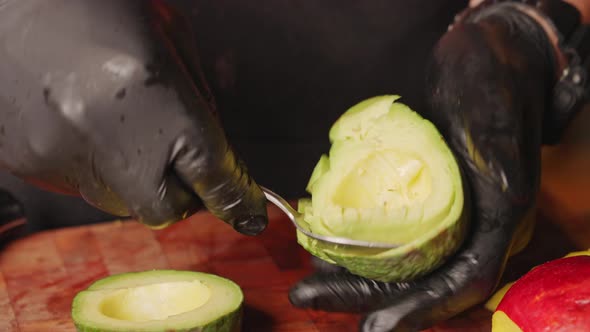Close up handheld shot of a male chef cutting and scooping avocado flesh with a spoon. alt