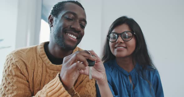 Multi ethnic couple receiving keys for new car alt
