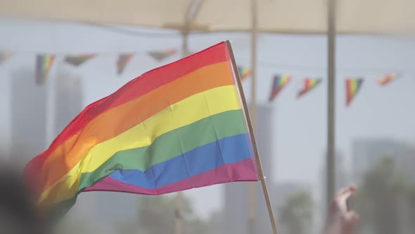 LGBTQ rainbow flag waving in slow motion during a pride parade with thousands of people
