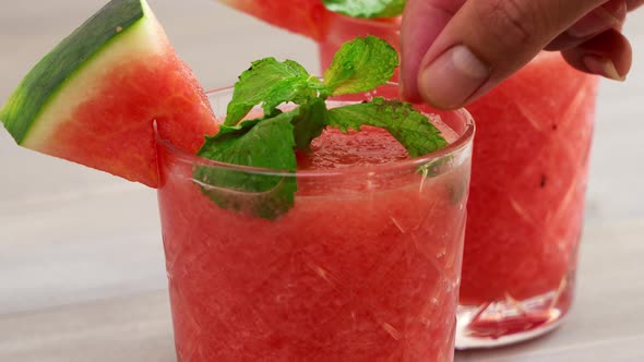 Healthy homemade watermelon fruit smoothies in the glasses being garnished with peppermint leaves