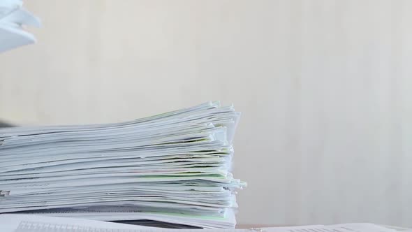 Human Putting a Stack of Sheets on a Desk at the Office. alt