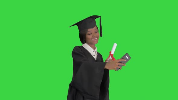 Happy African American Female Graduate Holding Diploma and Making Selfie on a Green Screen, Chroma alt