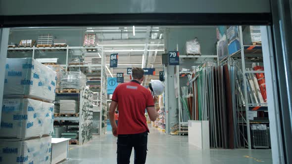 Sales consultant at a building materials supermarket comes out of the warehouse to the sales floor