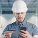 A Builder is Using Mobile Phone for Online Shopping with a Credit Card at Building Site - VideoHive Item for Sale