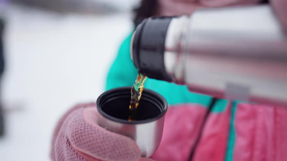 Closeup of Female Hands in Pink Mittens Pouring Tea From Thermos Outdoors alt