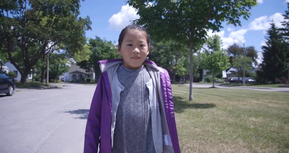 Young Asian girl walking to school on sunny day alt