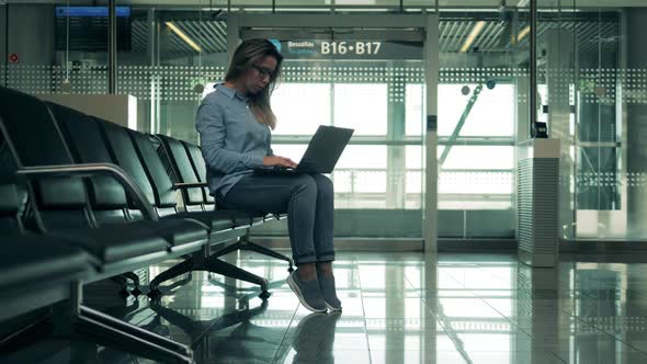 Empty Departure Lounge with a Lady Operating a Laptop alt