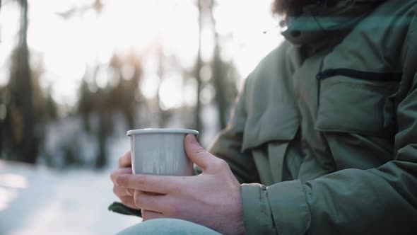 Man's Holding a Mug with Hot Drink in the Woods on a Winter Sunny Day in Camp