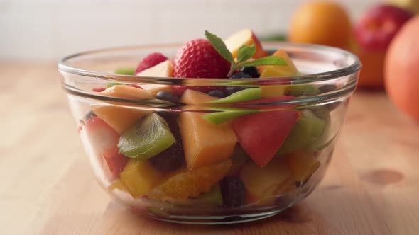 Camera follows putting fresh mint over fruit salad. Slow Motion. alt