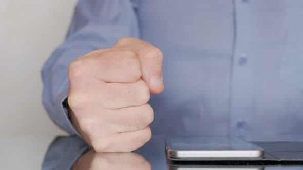 Boss Clenching His Fist Signaling Anger and Frustration As His Hand Rests on an Office Table alt
