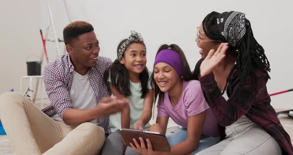 Joyful Parents and Their Daughters are Sitting on Floor of Apartment They Just Renovated Browsing alt